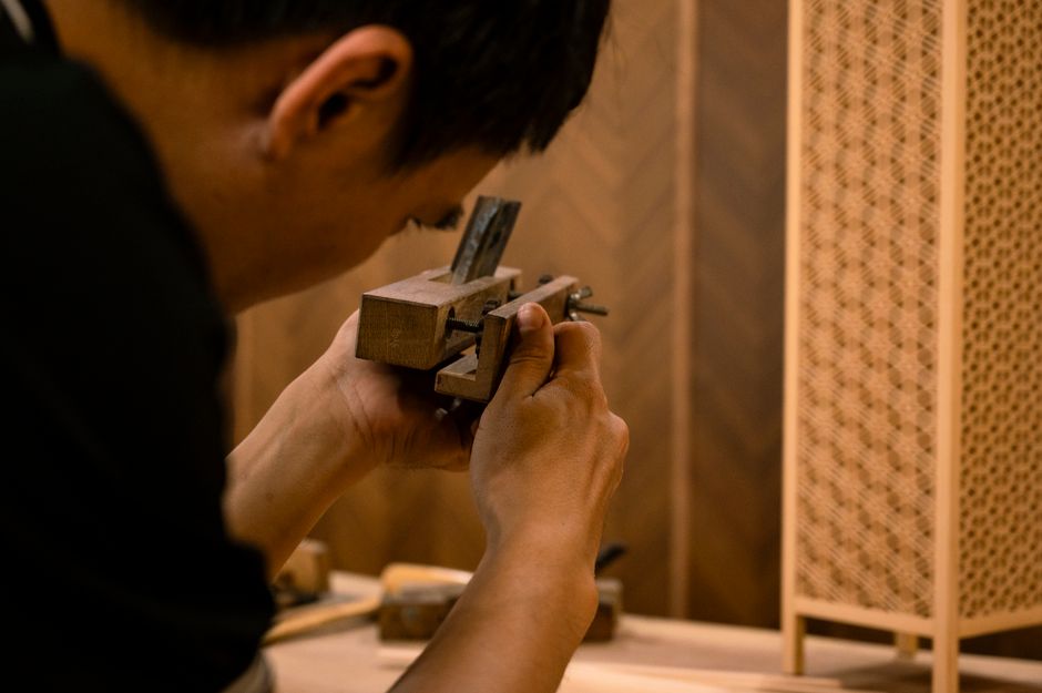 Skilled artisan working on traditional wood joinery technique indoors.